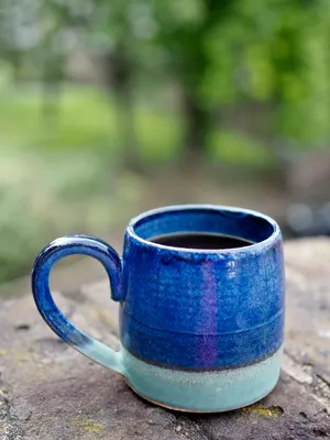 Caneca artesanal azul-cobalto sobre tronco de madeira